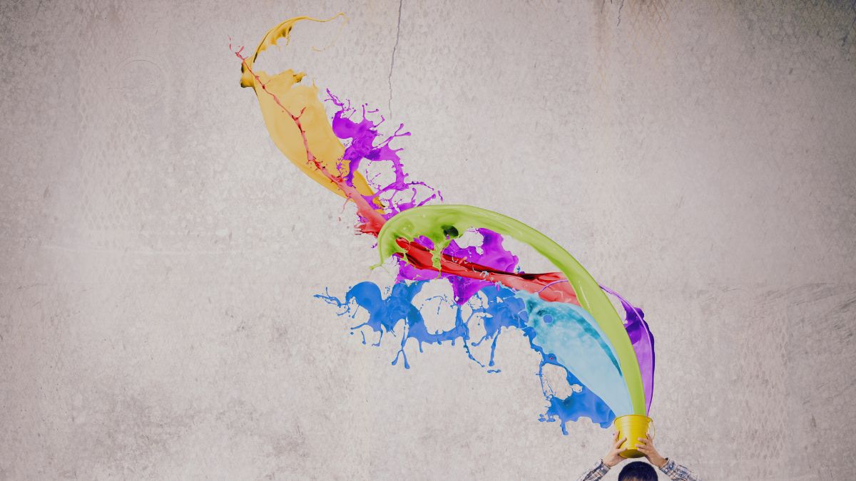 Abstract image of bright paint splashes in yellow, purple, green, red, and blue arcing across a light grey textured background, with a small figure at the bottom holding a yellow bucket.